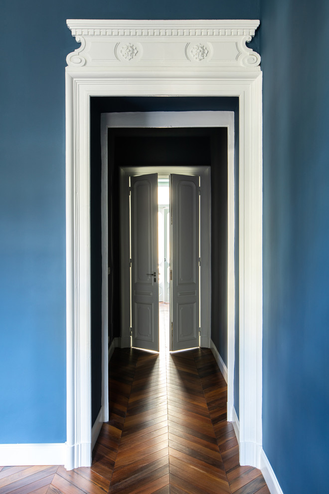 Imagen de distribuidor moderno con paredes azules, puerta doble, puerta de madera oscura y suelo de madera oscura