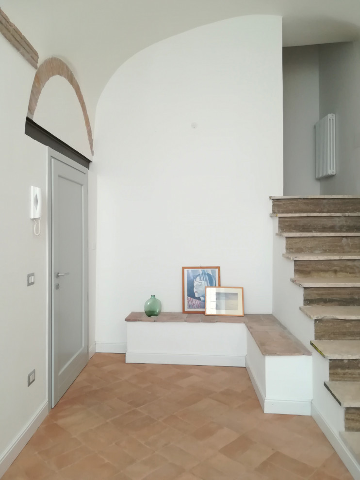 Exemple d'un hall d'entrée tendance de taille moyenne avec un mur blanc, un sol en brique, une porte simple, une porte grise, un sol marron, un plafond voûté et du lambris.