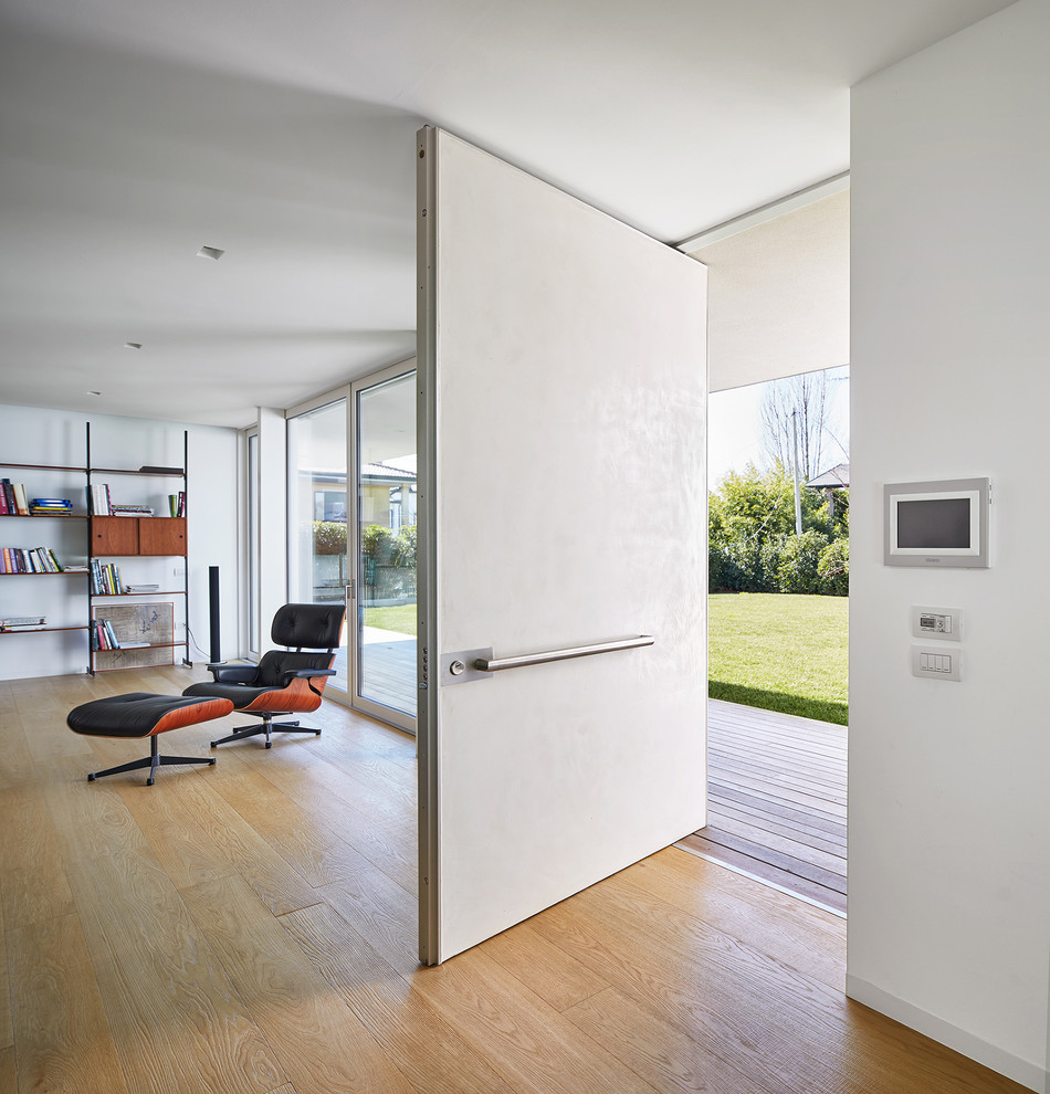 На фото: огромное фойе в стиле модернизм с белыми стенами, светлым паркетным полом и белой входной дверью с