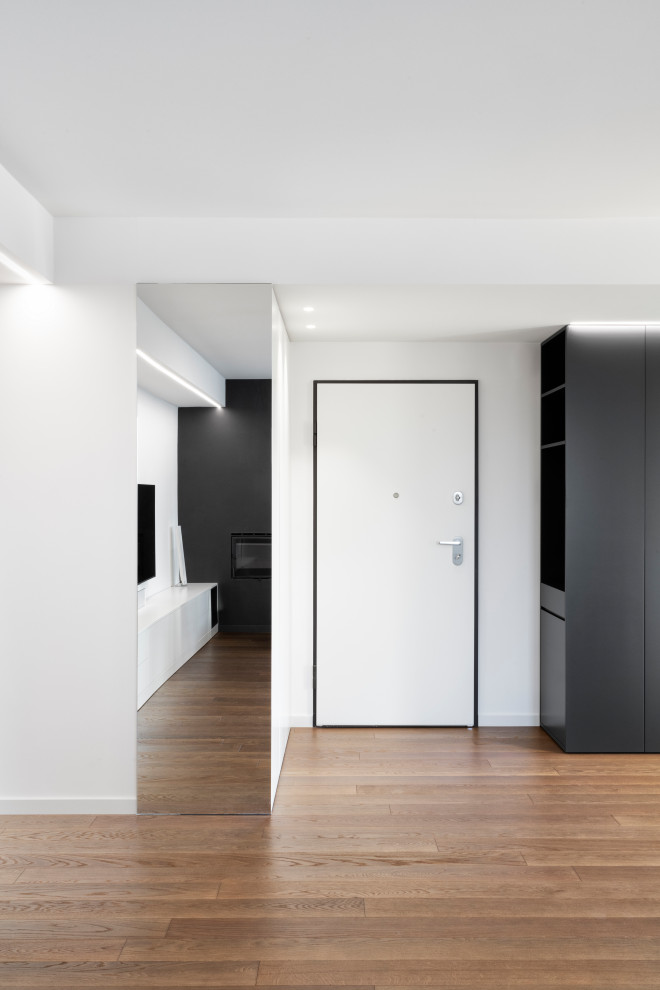 Großer Moderner Eingang mit dunklem Holzboden, Einzeltür und weißer Haustür in Mailand