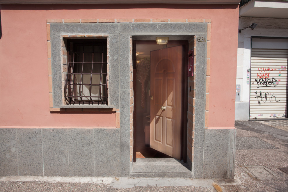 Lantlig inredning av en liten ingång och ytterdörr, med rosa väggar, en enkeldörr och en brun dörr