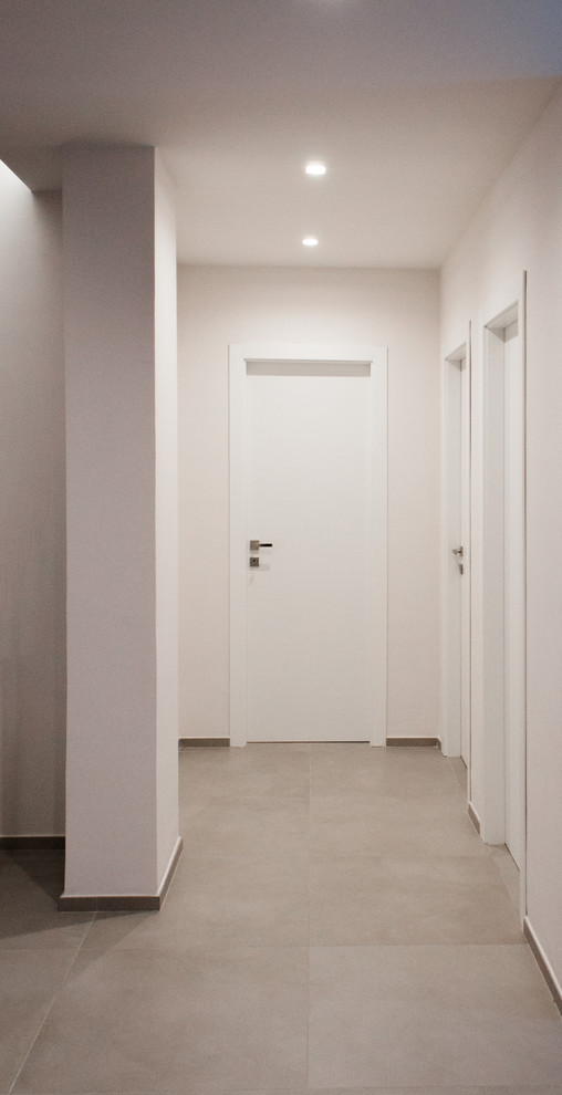 Ispirazione per un ingresso o corridoio minimal con pareti grigie, pavimento in gres porcellanato e pavimento grigio