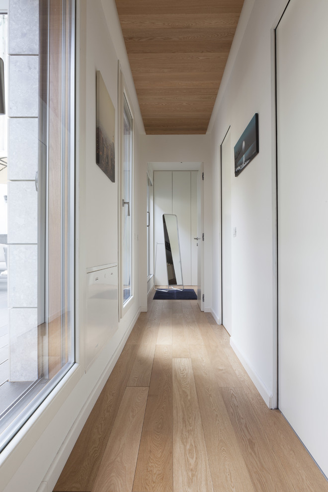Inspiration for a small contemporary light wood floor hallway remodel in Milan with white walls