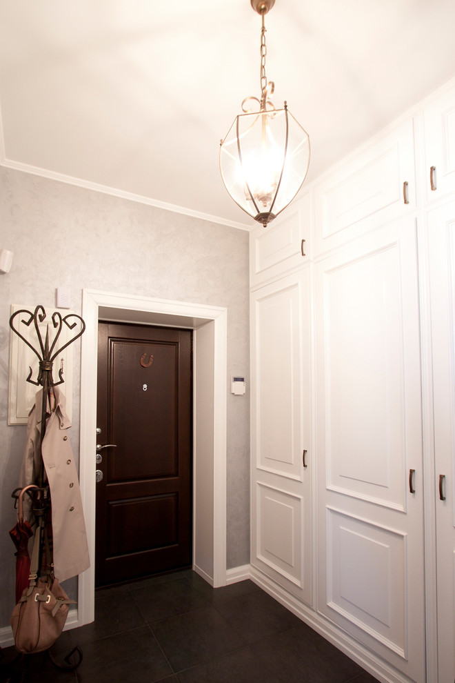 На фото: фойе среднего размера в классическом стиле с серыми стенами, полом из керамогранита, одностворчатой входной дверью, коричневой входной дверью и серым полом с