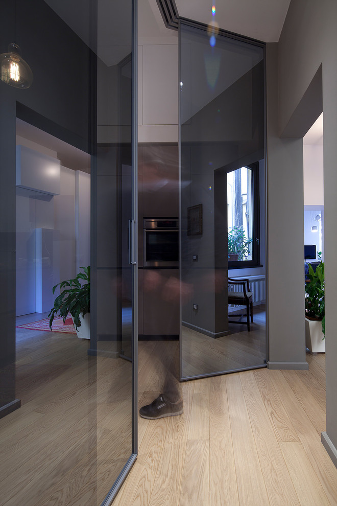 Réalisation d'une grande entrée design avec un couloir, un mur gris, parquet clair, une porte double et une porte en verre.