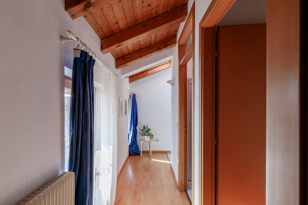 Esempio di un piccolo ingresso o corridoio minimal con pareti bianche e pavimento in legno massello medio