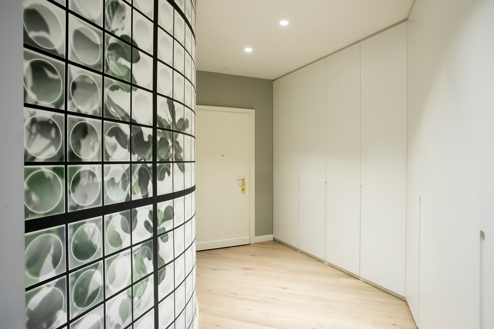 Immagine di un ingresso di medie dimensioni con pareti grigie, parquet chiaro, una porta singola e una porta bianca
