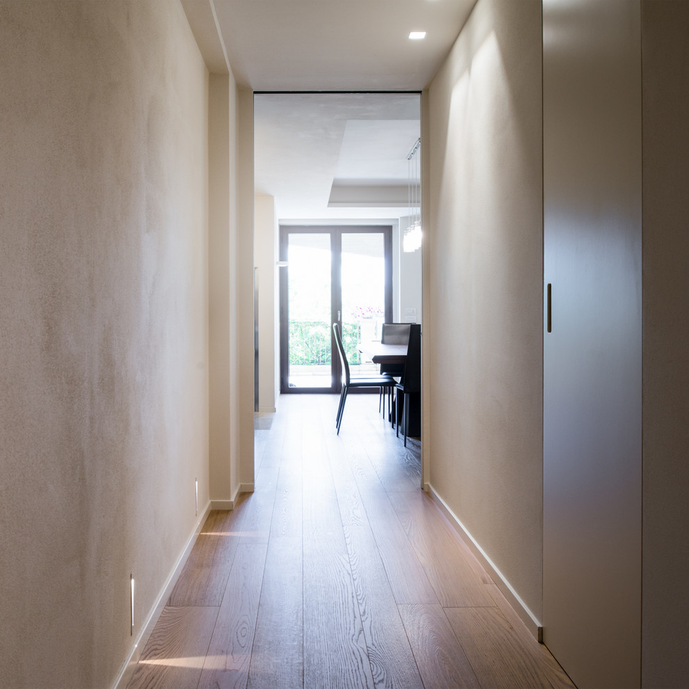 Exemple d'un couloir tendance de taille moyenne avec un mur blanc, parquet clair et un sol beige.