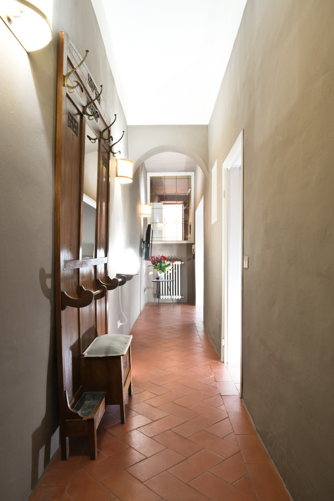 Idée de décoration pour un petit couloir minimaliste avec un mur gris, tomettes au sol et un sol orange.