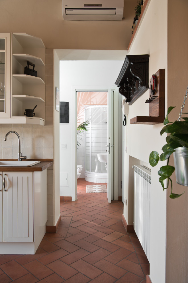 Идея дизайна: маленькое фойе в современном стиле с бежевыми стенами, полом из терракотовой плитки, одностворчатой входной дверью, белой входной дверью и оранжевым полом для на участке и в саду