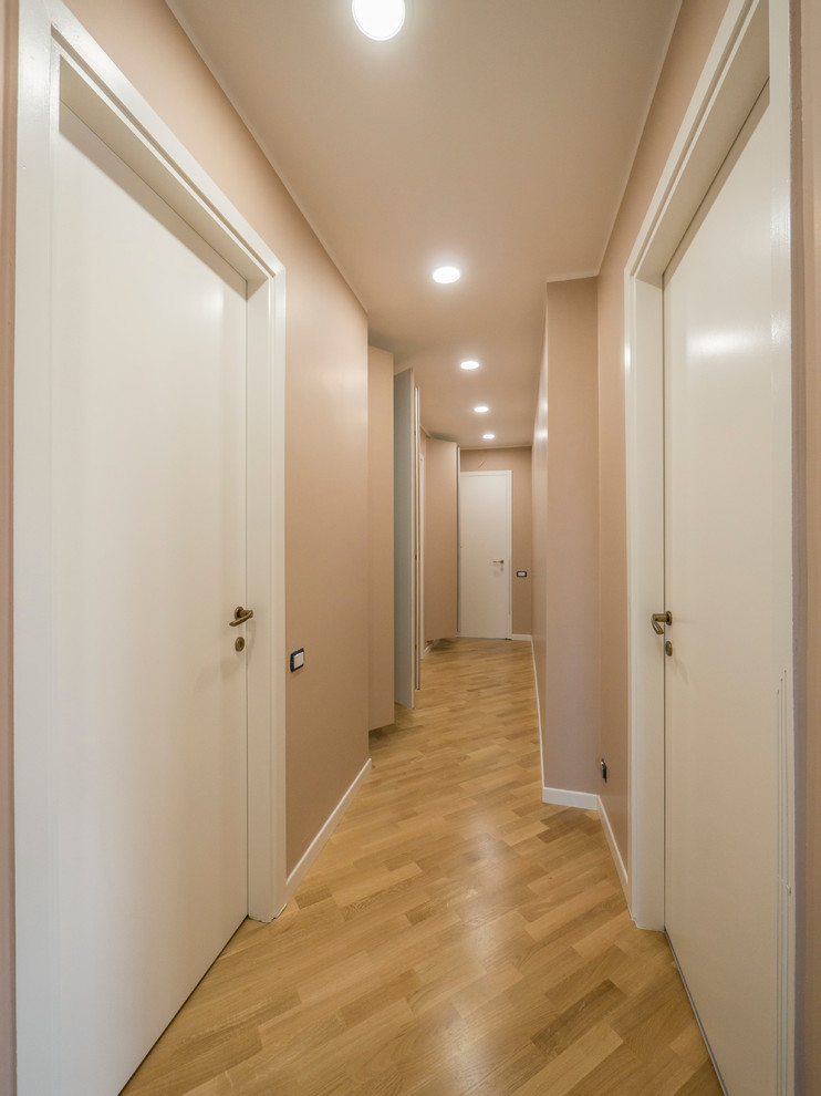 Foto de recibidores y pasillos modernos de tamaño medio con paredes beige y suelo de madera clara