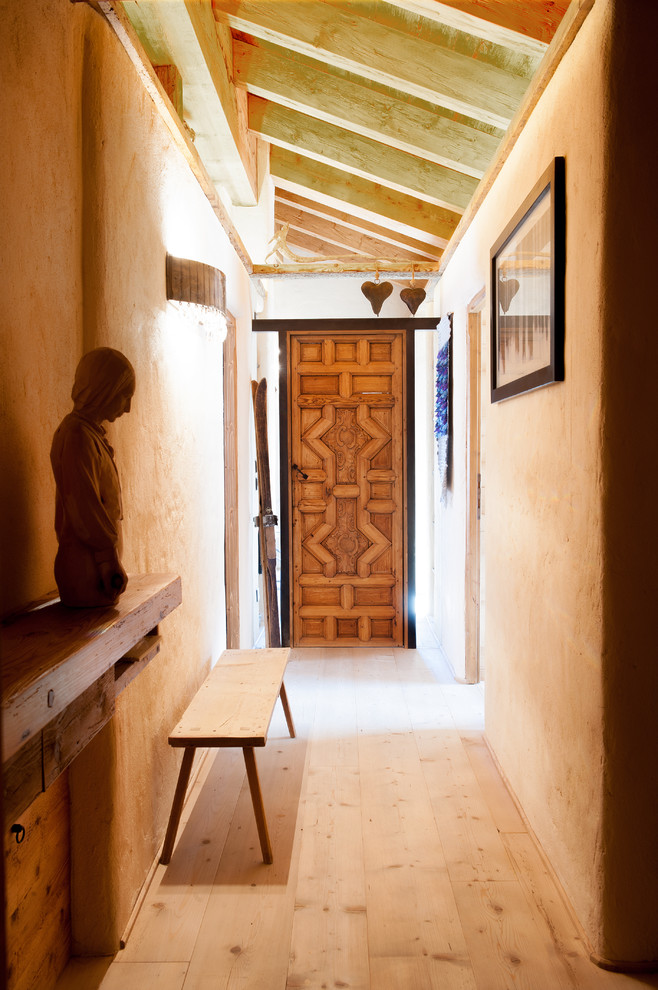 Esempio di un corridoio rustico con parquet chiaro, pareti beige e una porta in legno bruno