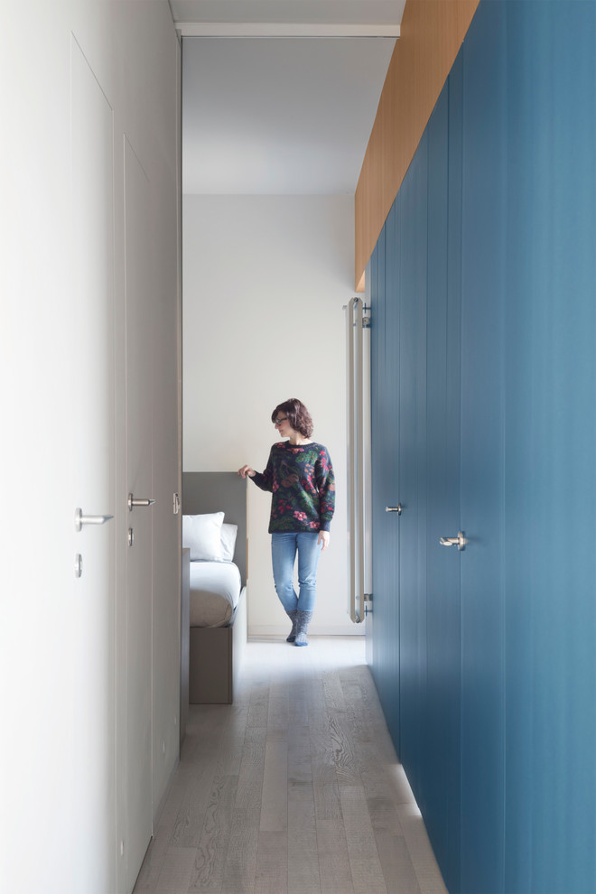 Ejemplo de recibidores y pasillos minimalistas pequeños con paredes azules, suelo de madera clara y suelo gris
