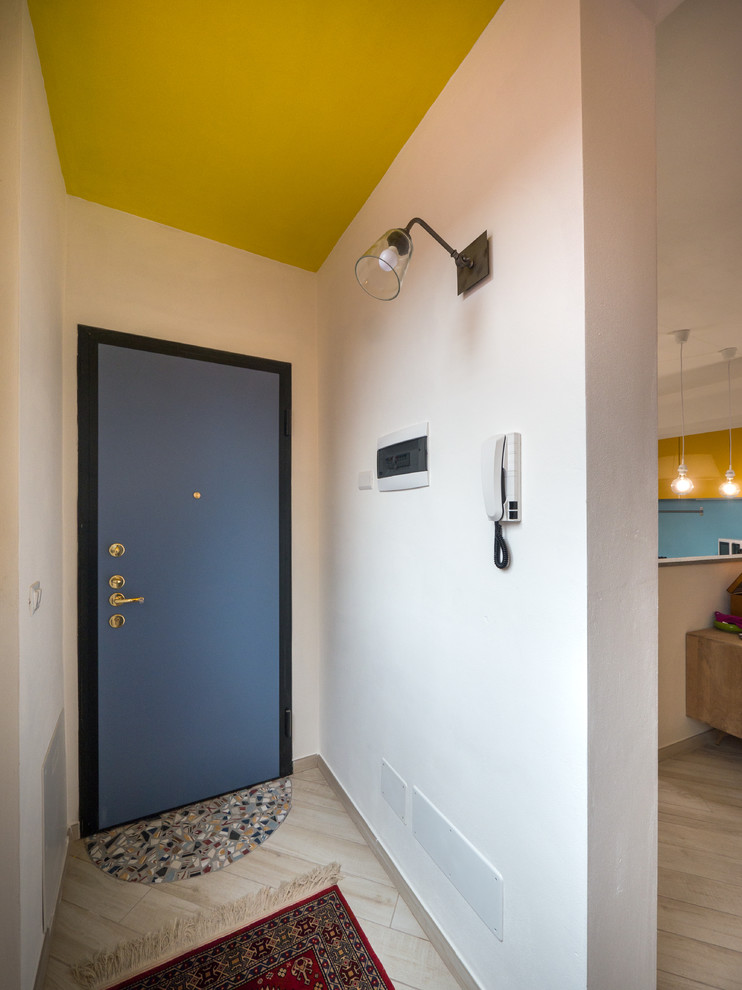 Immagine di un piccolo corridoio boho chic con pareti bianche, pavimento in gres porcellanato, una porta singola e una porta blu