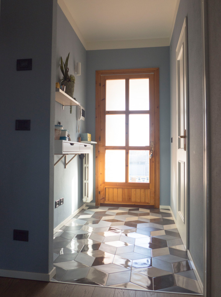 Inspiration för små moderna foajéer, med blå väggar, klinkergolv i porslin, en enkeldörr, ljus trädörr och flerfärgat golv