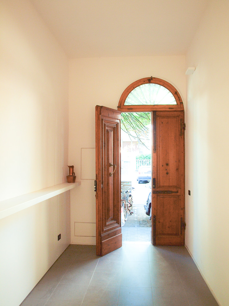 На фото: фойе среднего размера в современном стиле с белыми стенами, полом из керамогранита, двустворчатой входной дверью и входной дверью из темного дерева с