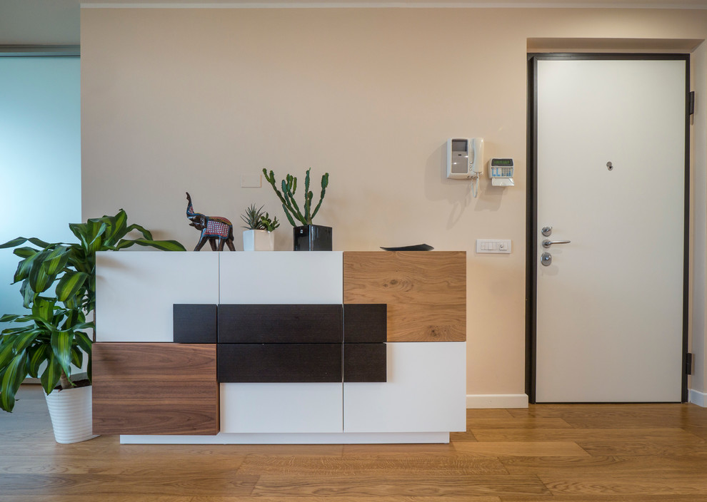 This is an example of a large contemporary entrance in Milan with light hardwood flooring, beige walls, a single front door and a white front door.