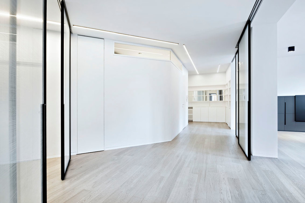 Modelo de entrada contemporánea extra grande con paredes blancas, suelo de madera clara, puerta blanca y suelo beige