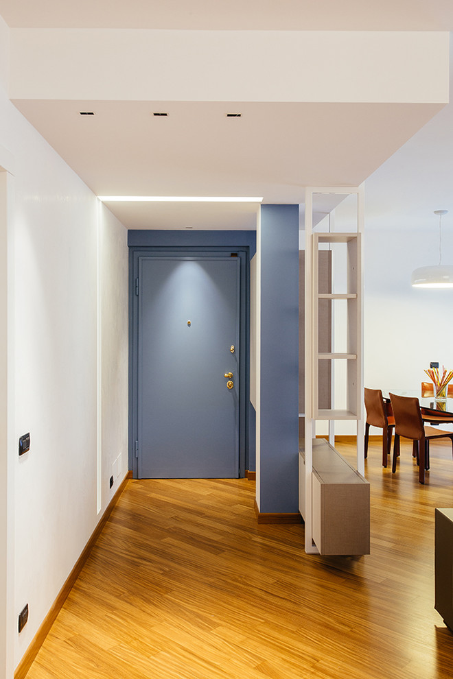 Idee per un corridoio minimal con pavimento in legno massello medio e una porta blu