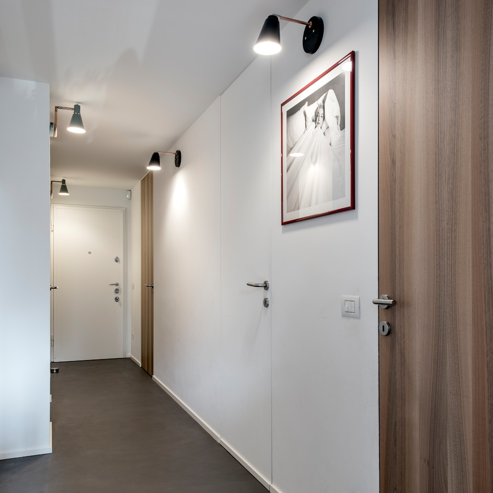 На фото: коридор среднего размера в скандинавском стиле с белыми стенами, бетонным полом и серым полом с