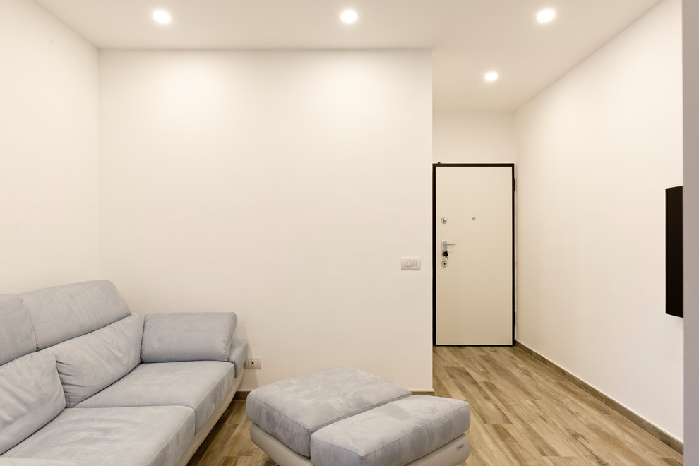Immagine di un piccolo ingresso design con pareti bianche, pavimento in gres porcellanato, una porta a pivot, una porta in legno chiaro e pavimento marrone