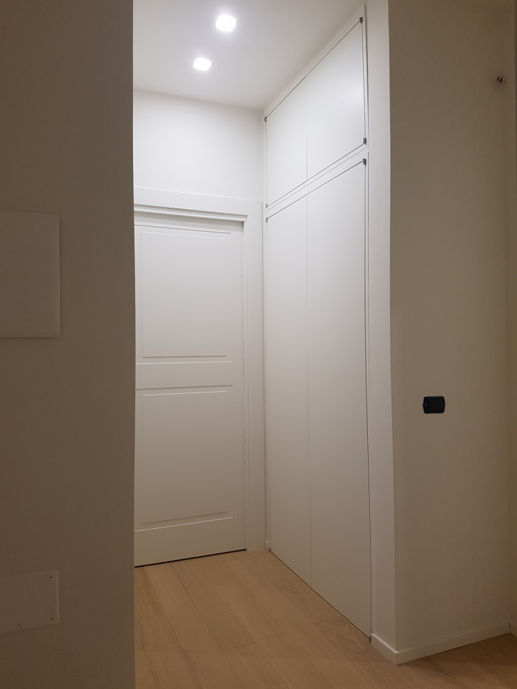 Immagine di un ingresso o corridoio minimalista di medie dimensioni con pareti bianche e parquet chiaro
