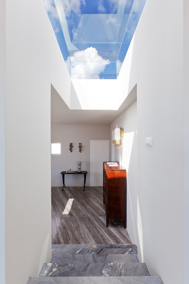 Cette image montre un couloir minimaliste de taille moyenne avec un mur blanc et un sol en marbre.