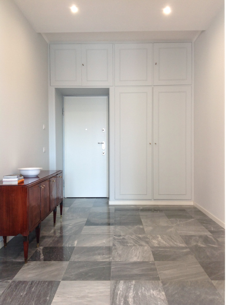 Modern inredning av en stor foajé, med grå väggar, marmorgolv, en enkeldörr, en vit dörr och grått golv