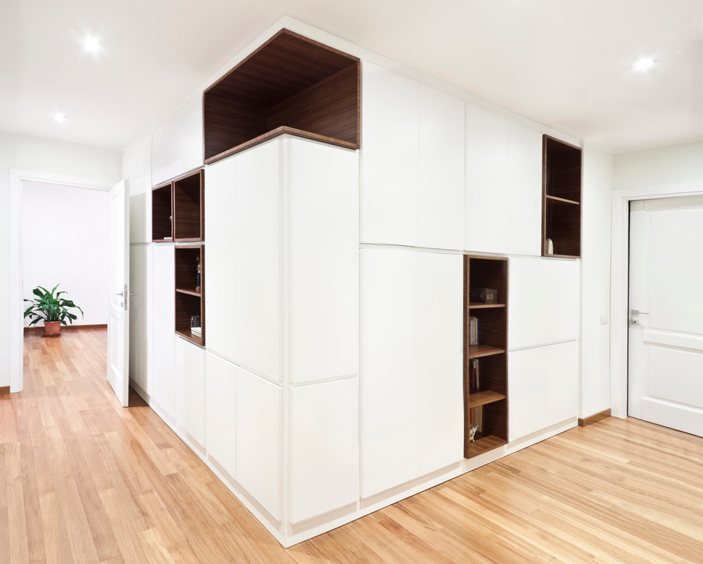 Foto på en minimalistisk hall, med vita väggar och ljust trägolv