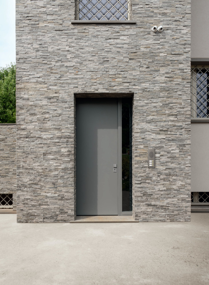Exemple d'une porte d'entrée tendance avec une porte simple, une porte grise et un mur en parement de brique.