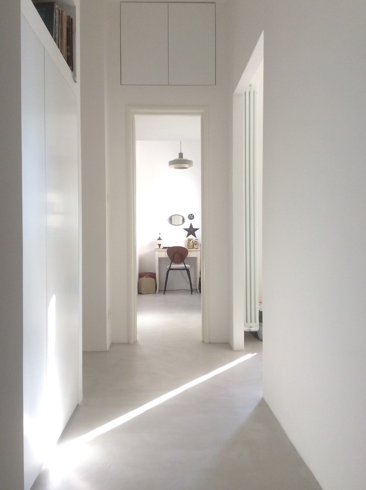 Ispirazione per un ingresso o corridoio design di medie dimensioni con pareti bianche e pavimento in cemento