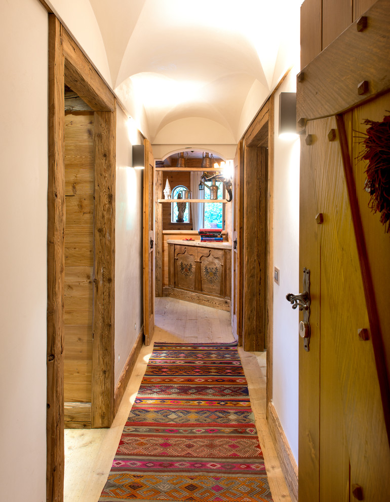Esempio di un ingresso o corridoio rustico di medie dimensioni con pareti bianche e pavimento in legno massello medio
