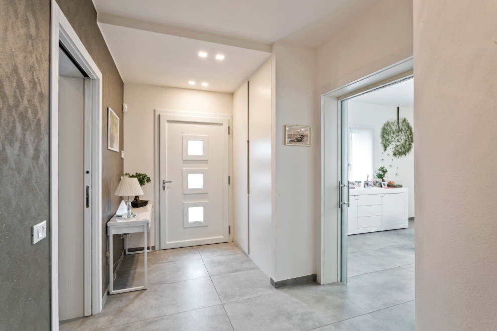 Inspiration pour un hall d'entrée minimaliste de taille moyenne avec un mur gris, un sol en carrelage de porcelaine, une porte simple, une porte blanche et un sol gris.