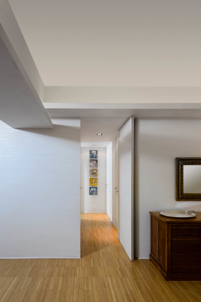 Inspiration pour un grand couloir design avec un mur blanc, parquet clair et un sol beige.