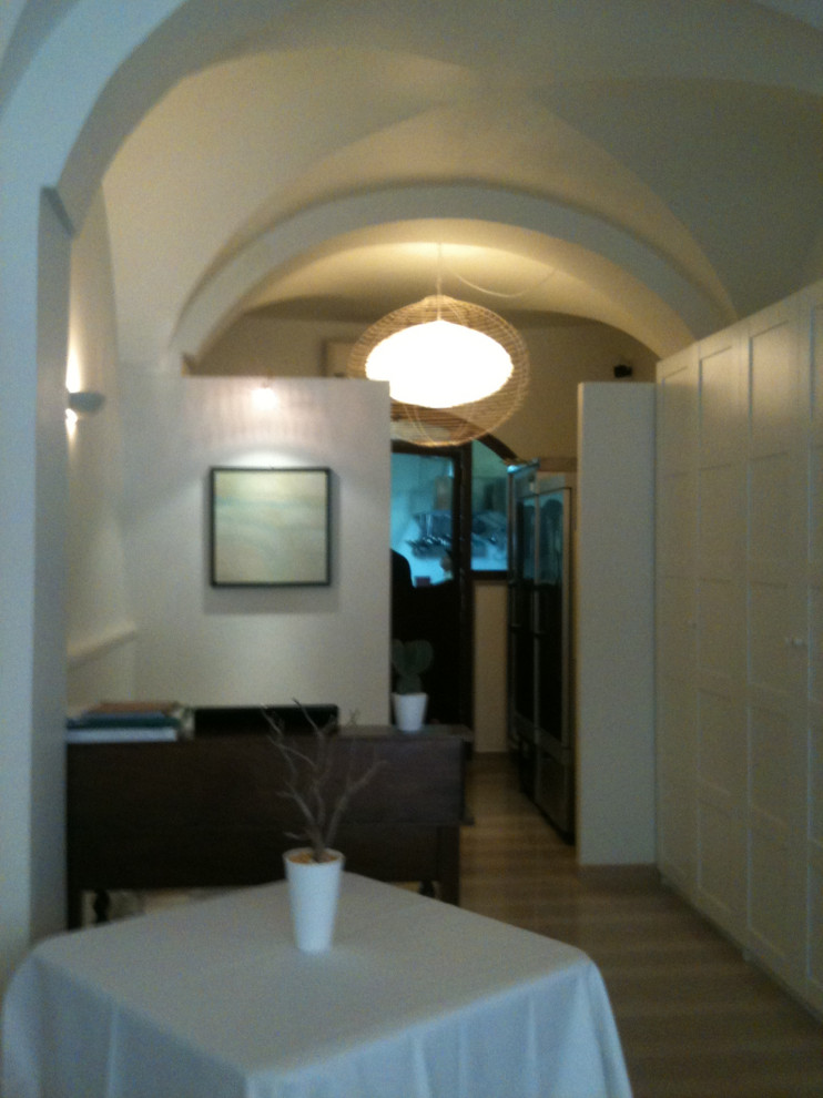 Foto de distribuidor abovedado mediterráneo pequeño con paredes blancas, suelo de piedra caliza, puerta doble, puerta de madera en tonos medios y suelo beige