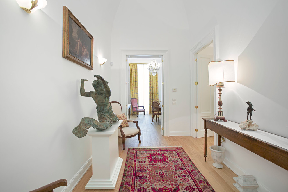 This is an example of a traditional entrance in Bari with white walls and light hardwood flooring.