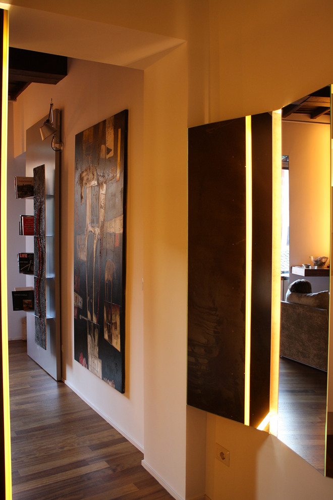Esempio di un piccolo corridoio minimal con pareti bianche, pavimento in legno massello medio, una porta singola, una porta in legno chiaro e pavimento marrone