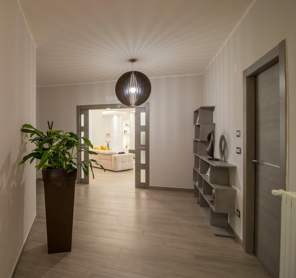 Immagine di un grande corridoio minimalista con pareti beige, pavimento in gres porcellanato, una porta singola, una porta in legno scuro e pavimento multicolore