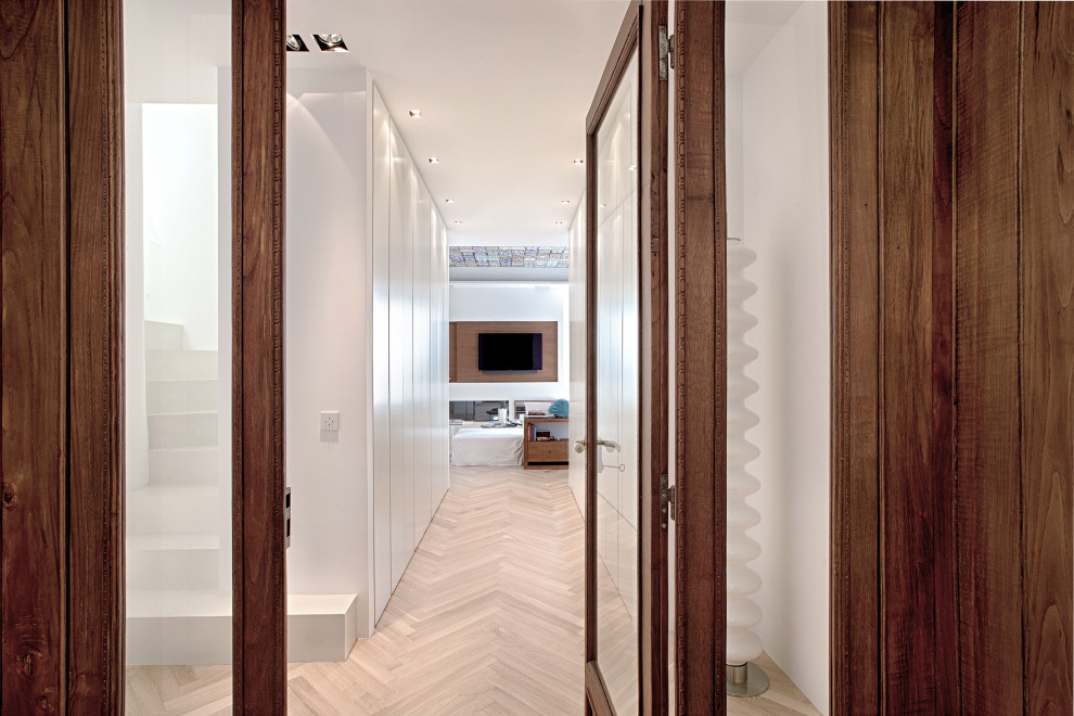 Example of a trendy light wood floor, tray ceiling and wall paneling entryway design in Other with white walls and a medium wood front door
