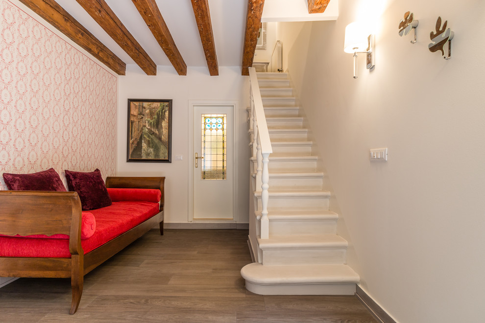 Стильный дизайн: фойе в средиземноморском стиле с одностворчатой входной дверью, розовыми стенами, светлым паркетным полом и белой входной дверью - последний тренд