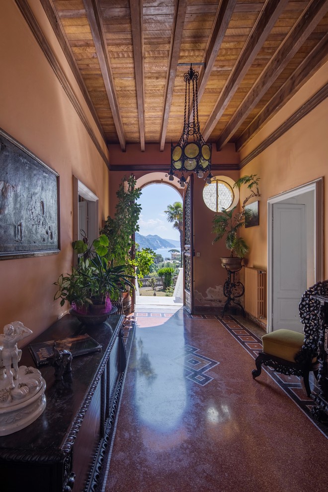 Idée de décoration pour une entrée méditerranéenne avec un couloir, un mur marron, une porte double, une porte marron et un sol multicolore.