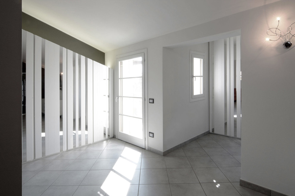 Foto di un grande ingresso minimal con pareti bianche, pavimento in gres porcellanato, una porta singola e una porta bianca