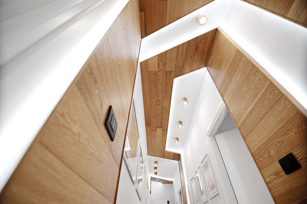 Ispirazione per un ingresso o corridoio minimalista di medie dimensioni con pareti bianche, parquet chiaro e pavimento marrone