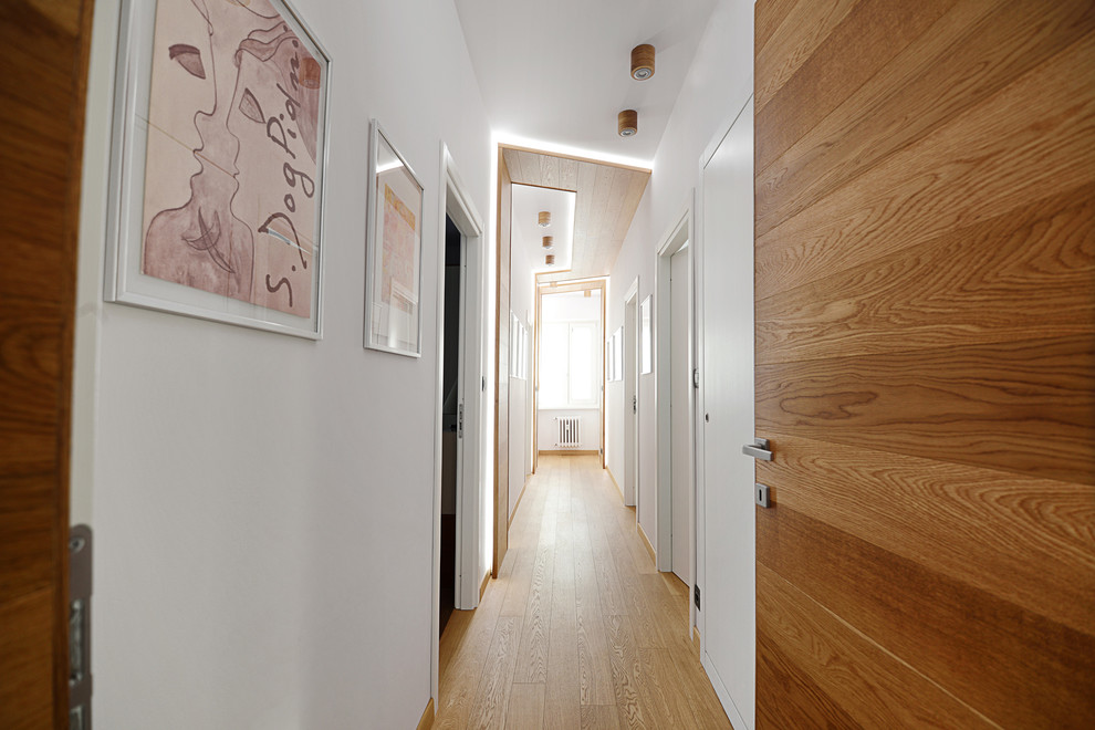 Immagine di un ingresso o corridoio contemporaneo di medie dimensioni con pareti bianche, parquet chiaro e pavimento marrone