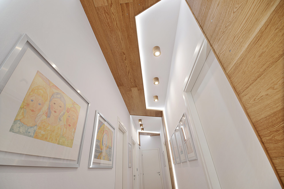 Esempio di un ingresso o corridoio minimalista di medie dimensioni con pareti bianche, parquet chiaro e pavimento marrone
