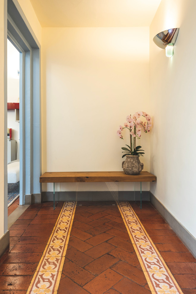 Foto på en liten funkis hall, med tegelgolv och brunt golv