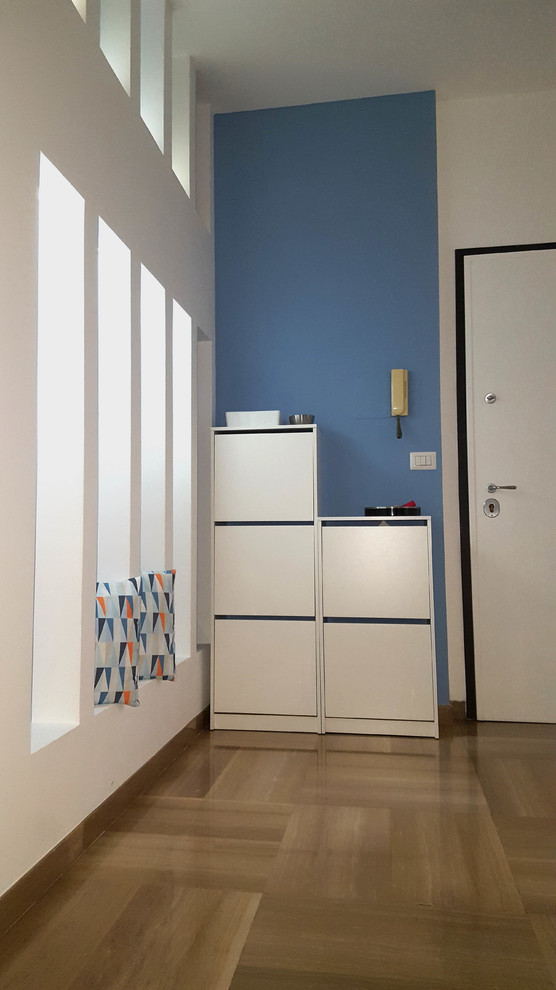 Imagen de distribuidor minimalista con paredes azules, suelo de mármol, puerta blanca y suelo beige