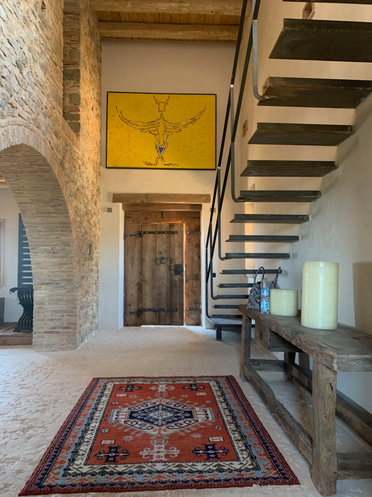 他の地域にある巨大な地中海スタイルのおしゃれな玄関ホール (ベージュの壁、木目調のドア、ベージュの床、ライムストーンの床) の写真