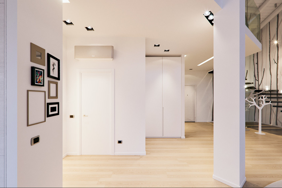 Photo of an expansive contemporary foyer in Milan with white walls, light hardwood flooring and a white front door.