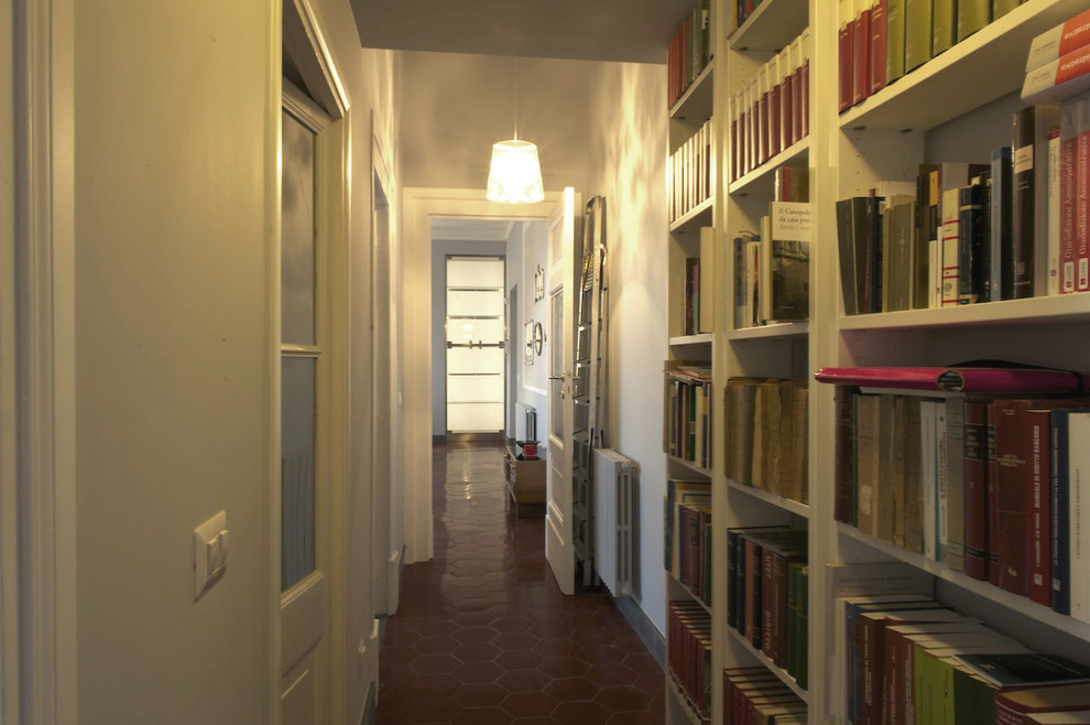 Exemple d'un grand couloir rétro avec un mur gris, sol en béton ciré et un sol rouge.
